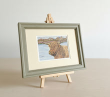 Load image into Gallery viewer, highland cow by a loch colouered pencil drawing by Helen Elizabeth Studios
